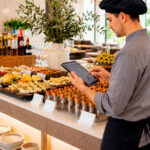 Chef gestionando el etiquetado digital del buffet desde una tablet en un hotel